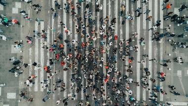Luchtfoto van een groot aantal mensen die een weg oversteken.
