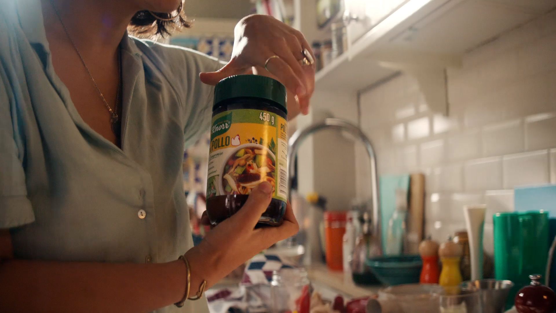 Een vrouw die een pot kippenbouillon opent in een lichte keuken.