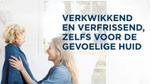 Een vrouw heeft een vriendelijke interactie met een kind dat in een blauwe handdoek is gewikkeld, in een lichte en luchtige badkamer.