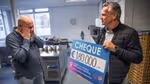 Op links Johan de Boterhammenman vol ongeloof kijkend naar cheque van €180.000 geschonken door Unilever.